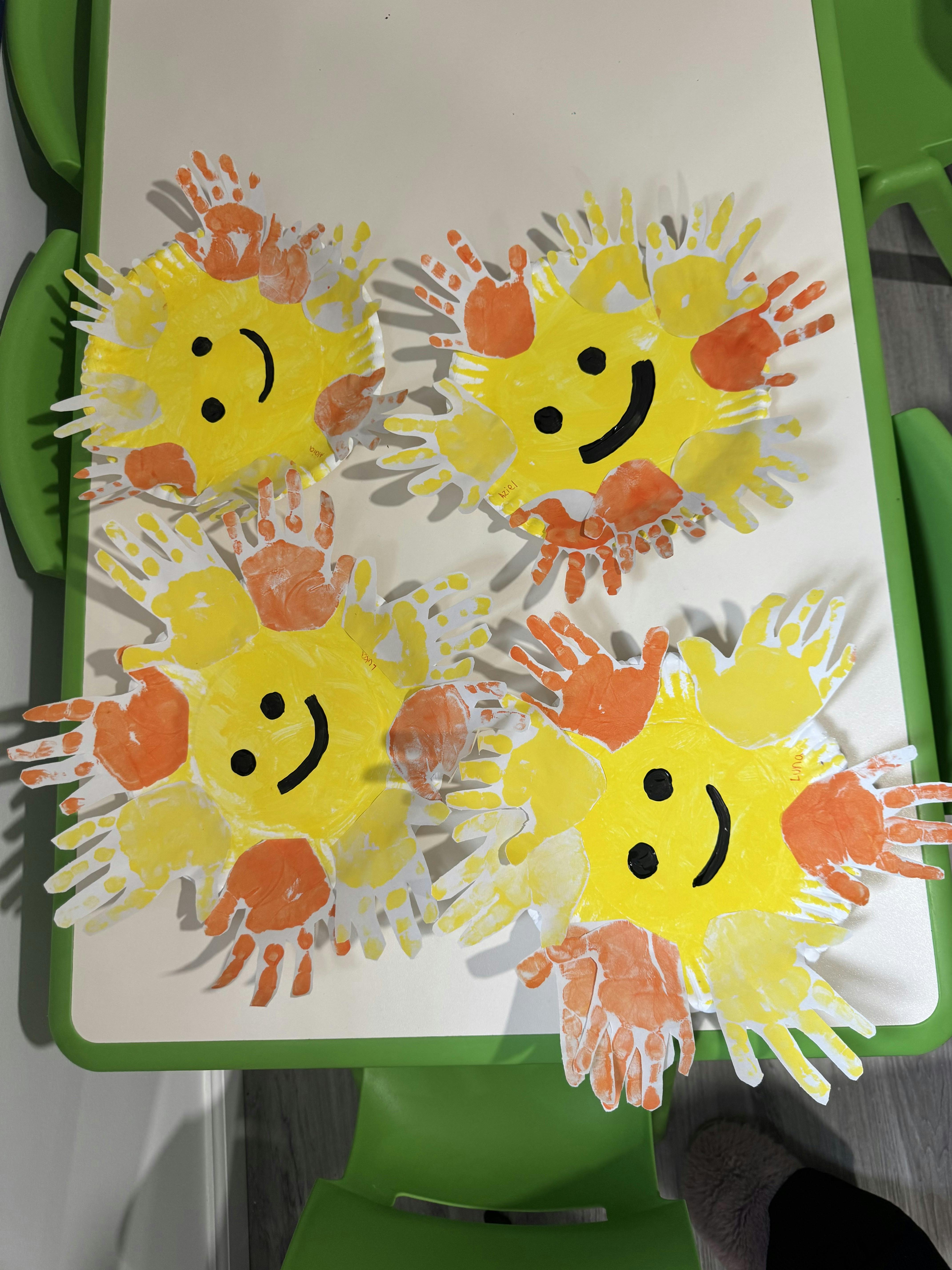 Four paper plate suns with painted handprints as rays