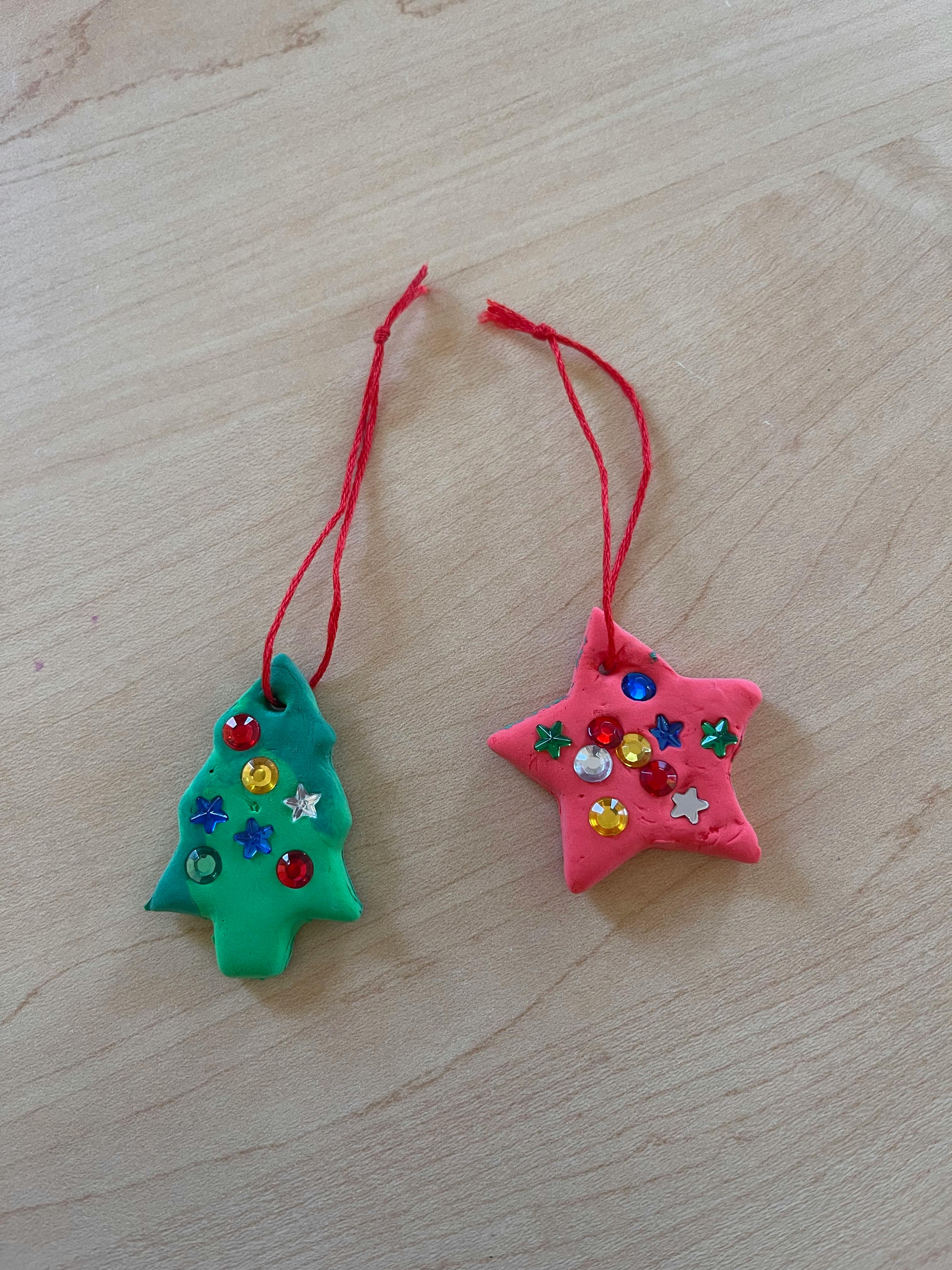 Two handmade ornaments, one green Christmas tree and one pink star, with glitter