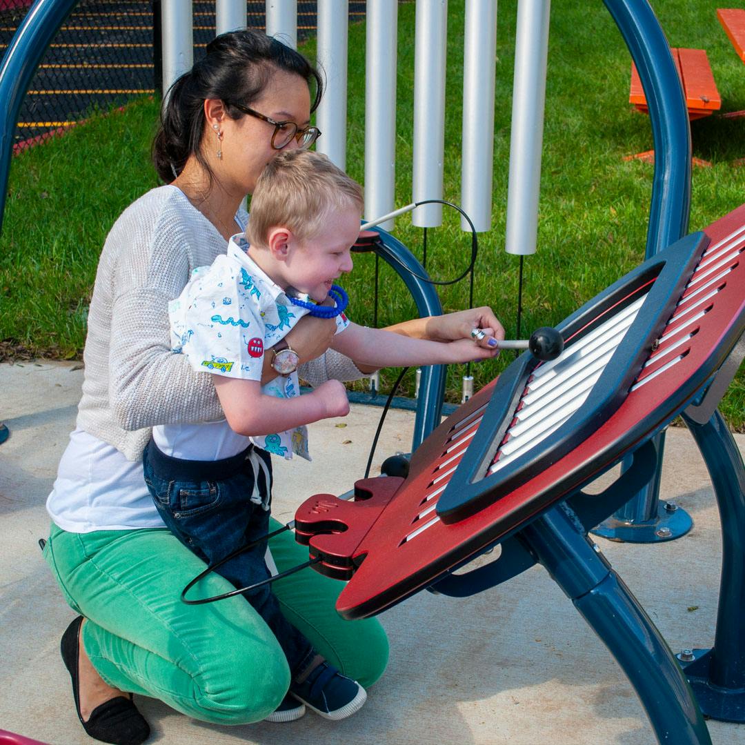 Person holding a child who is playing a musical instrument