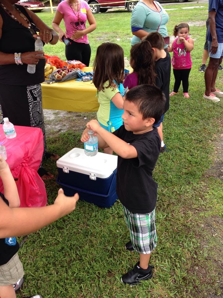 Child opening a water bottle on top of a cooler