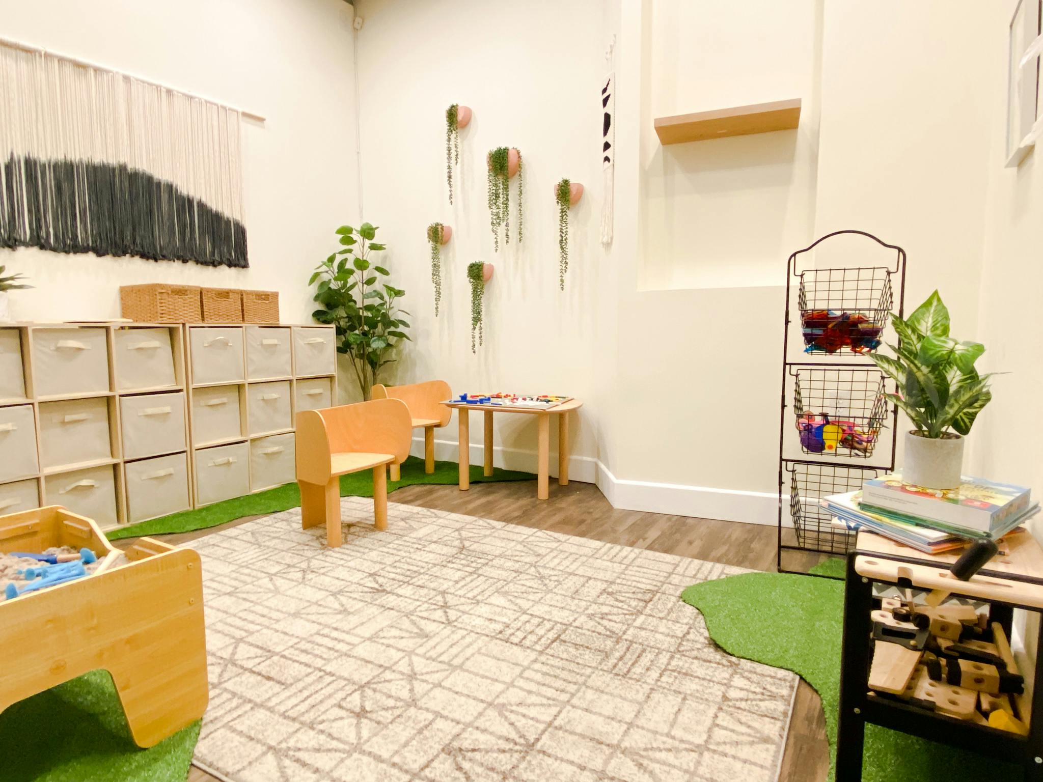 Children's play area with small tables and chairs, storage cubbies, and plants