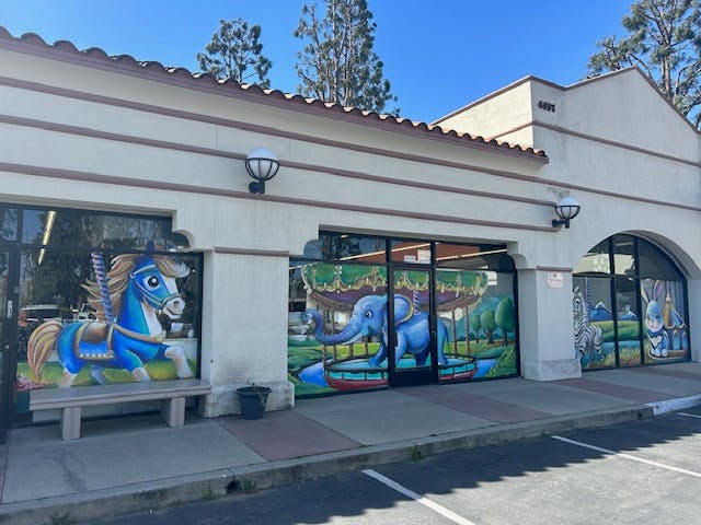 Storefront with window murals of a blue horse and an elephant