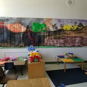 Children's play area with tables, toys, and a colorful mural