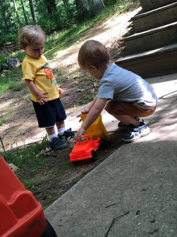 Two children playing with toy trucks outdoors
