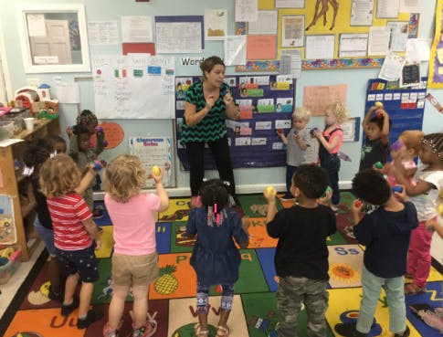 Adult leading a group of children in a classroom activity