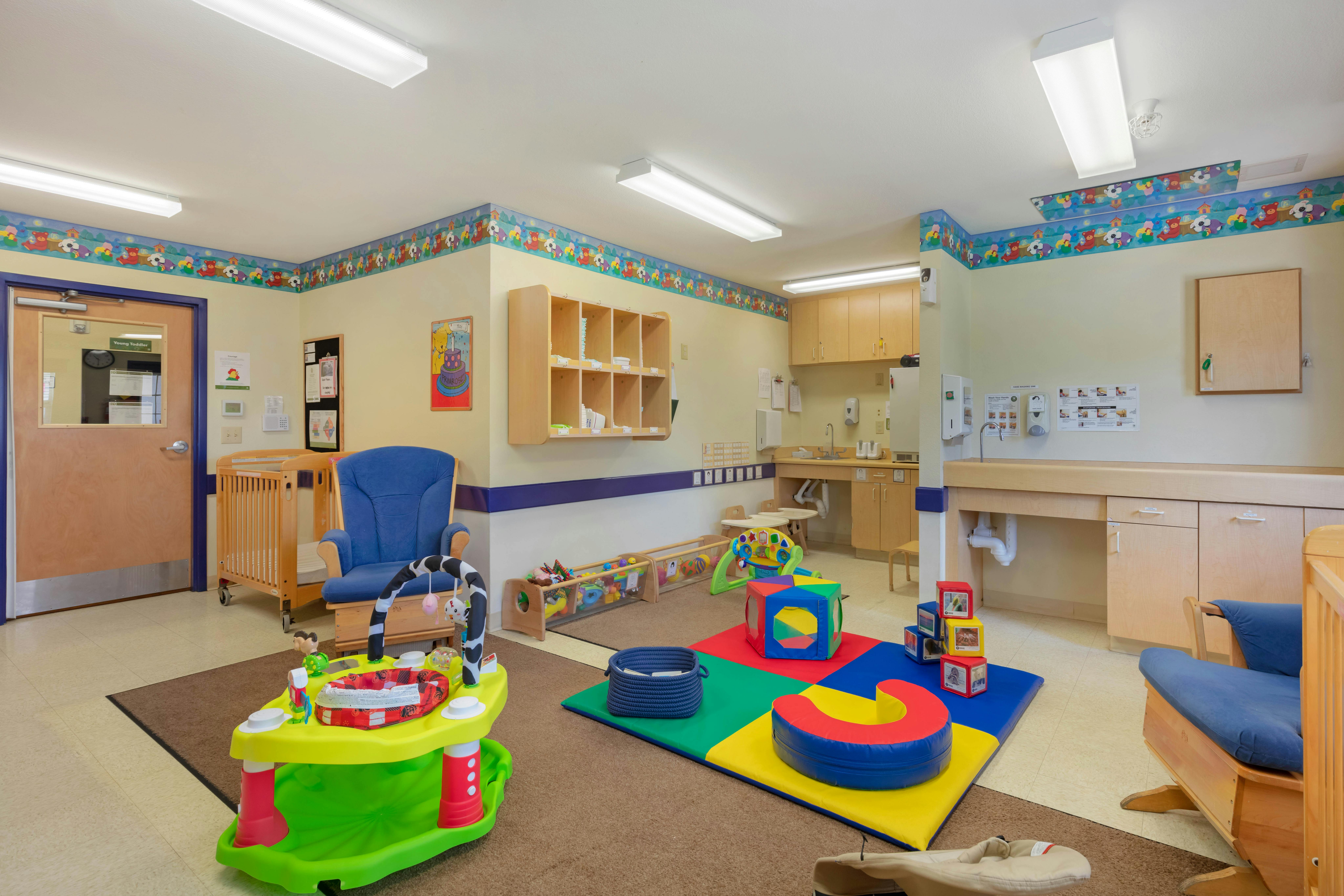 Colorful playroom with cribs, chairs, playmats, and toys