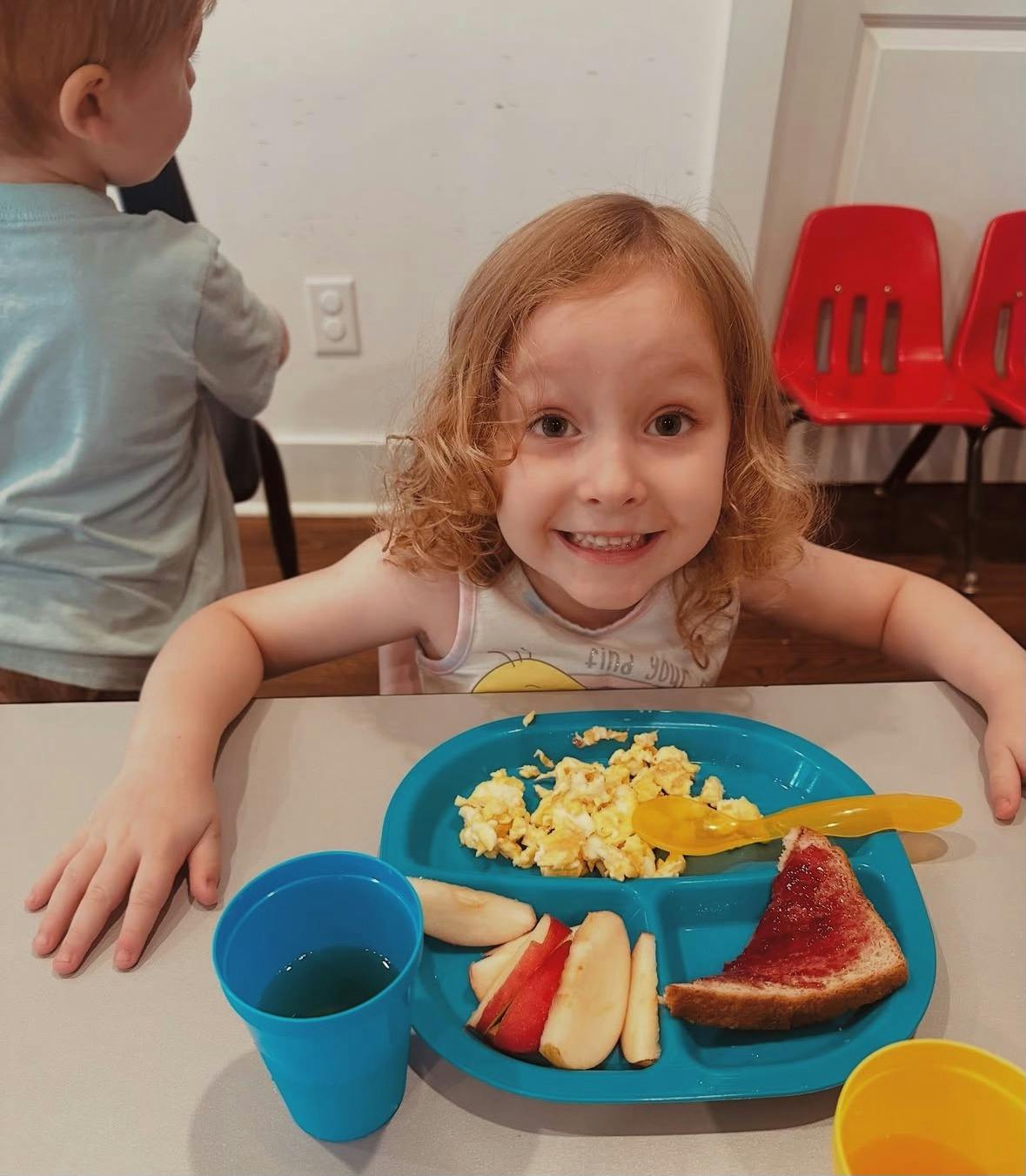 Child sitting at a table with a plate of food