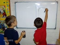 Two children drawing on a whiteboard