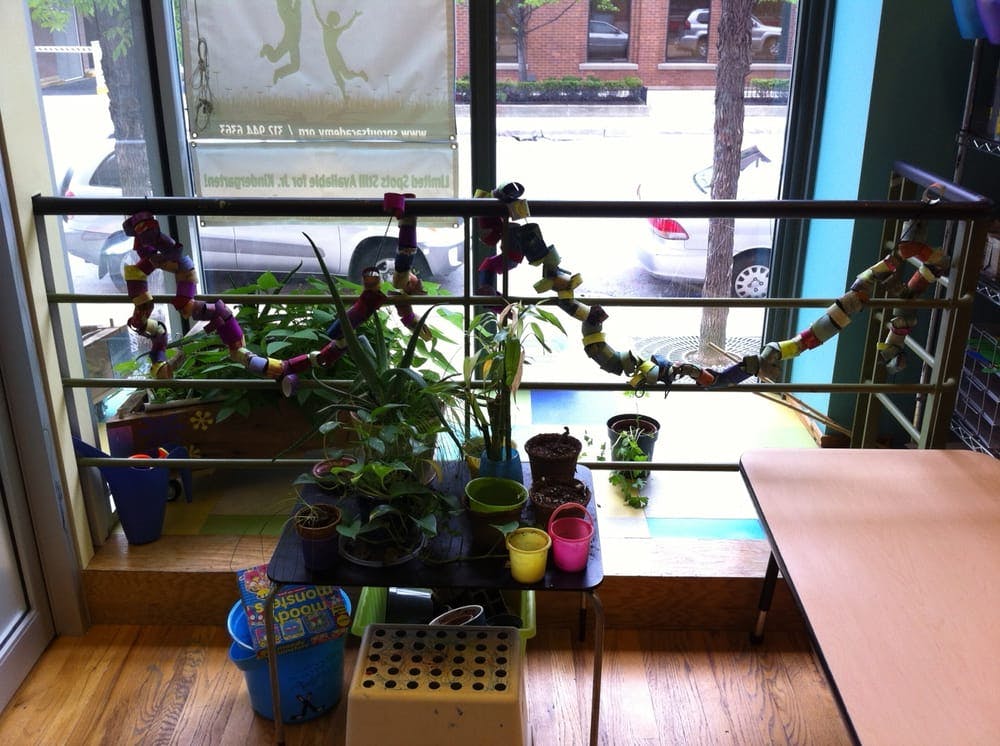 Potted plants and colorful containers on a table by a window