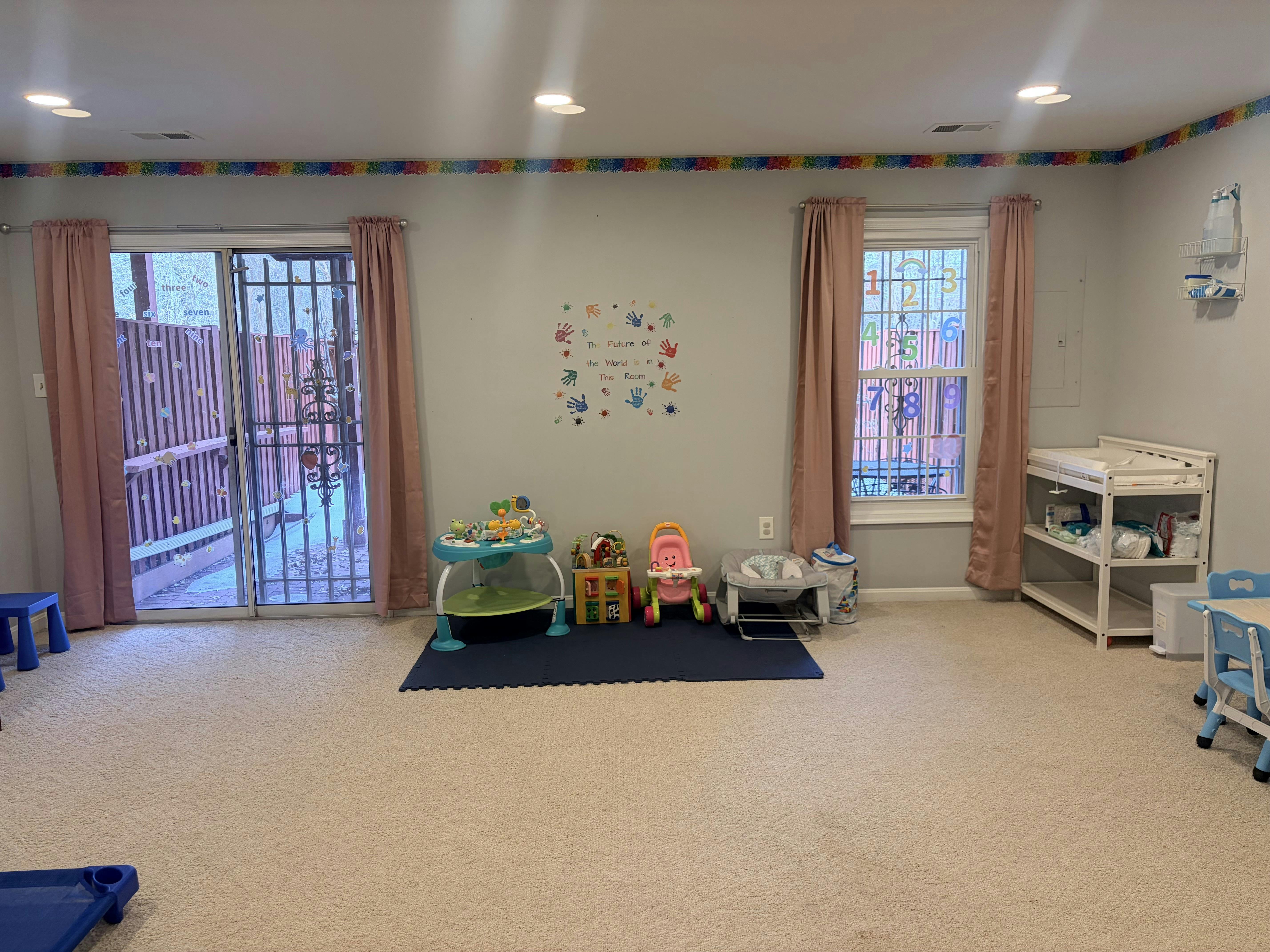 Childcare playroom with a changing table, toys, and a sliding door with bars