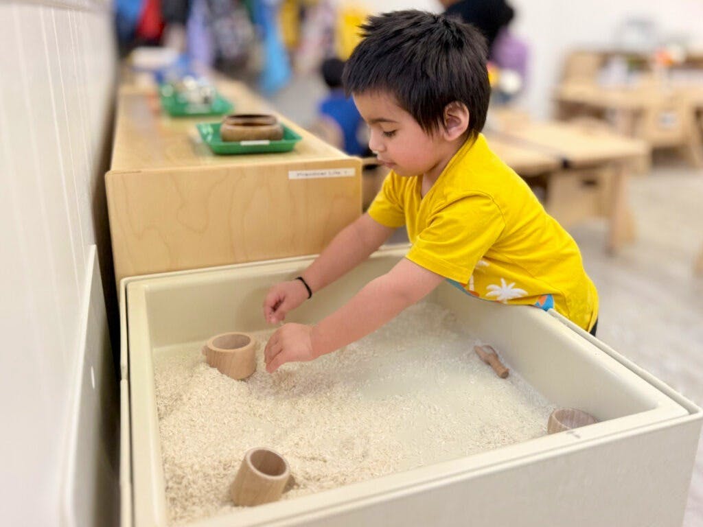 Child playing in a sensory bin filled with rice