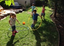 Children playing with hula hoops in a grassy yard