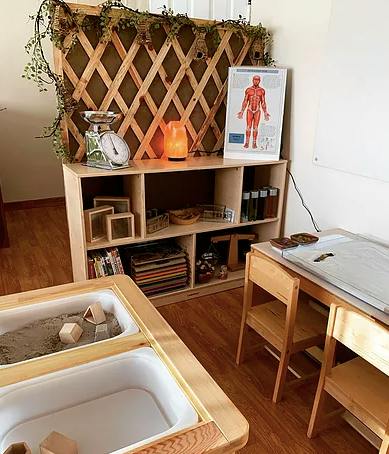 Classroom with a wooden lattice screen, shelves, and a sensory table