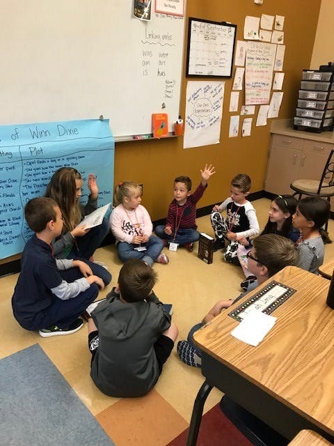 Adult reading to children sitting in a circle on the floor in a classroom