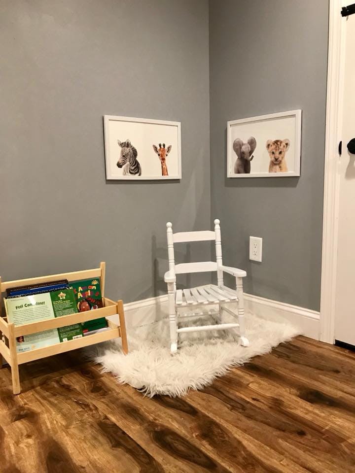 Small wooden bookshelf with books next to a white rocking chair on a rug