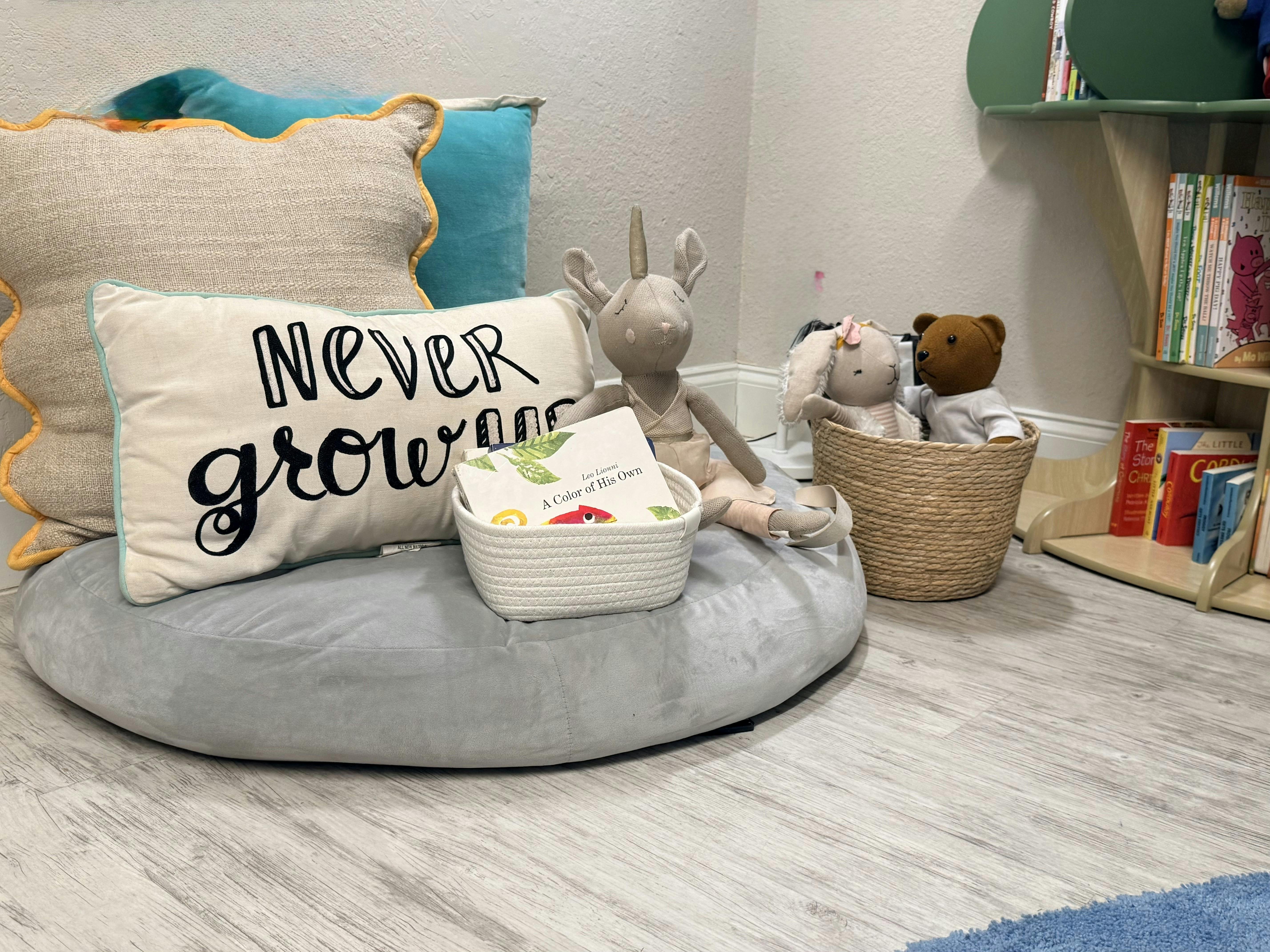 Pillows, stuffed animals, and books on a floor cushion in a child's reading nook