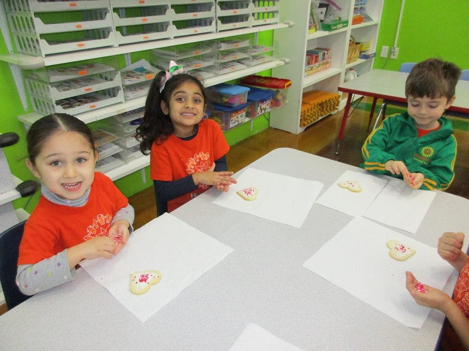 Three children decorating cookies at a table