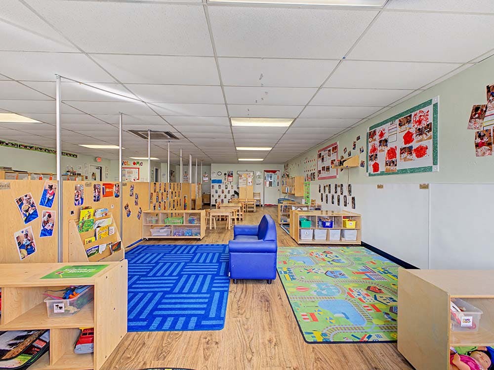 Classroom with cubbies, small tables and chairs, blue rugs, and a blue sofa