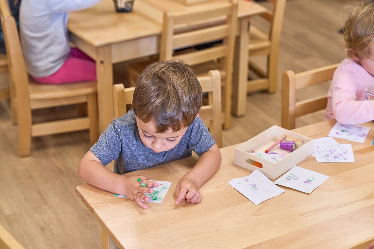 Child at a table looking at a small card