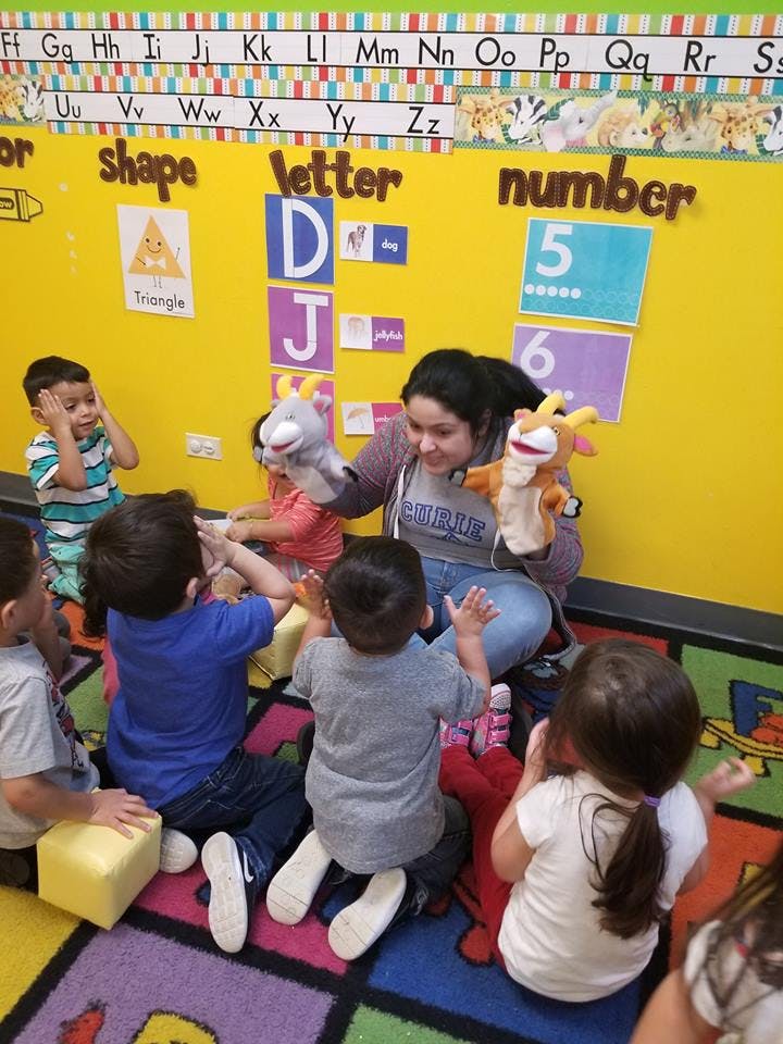Adult using puppets to interact with children in a classroom