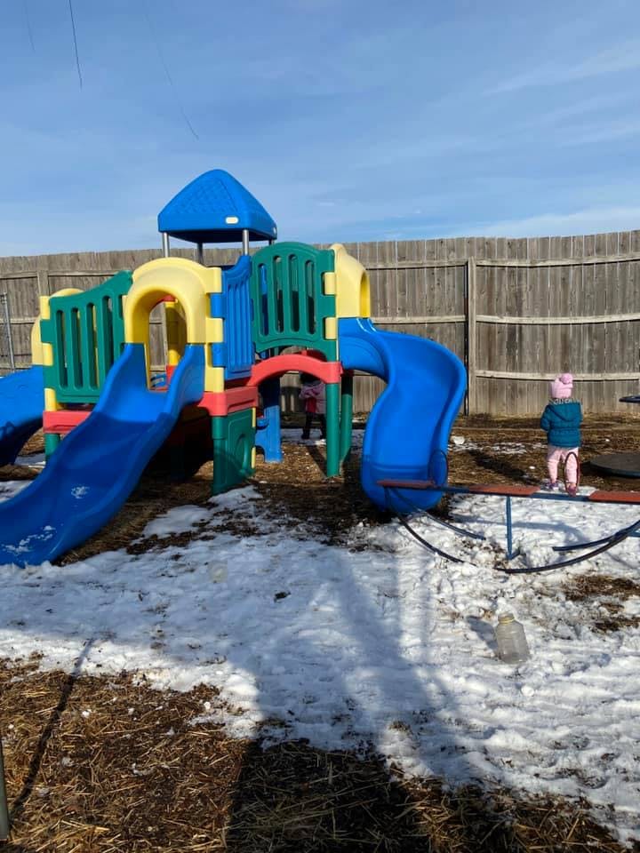 Child on a playground with snow on the ground