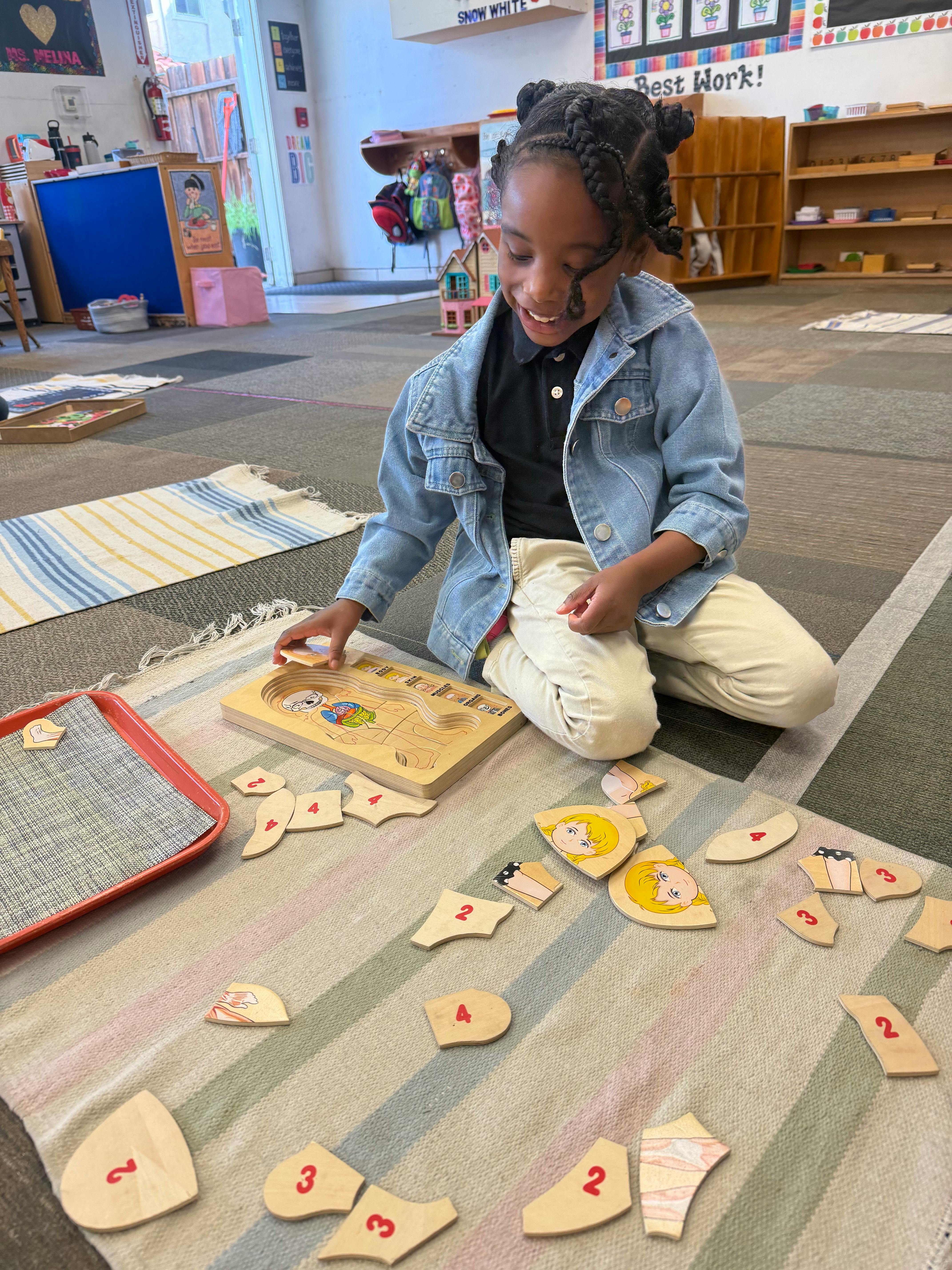 Child playing with a human anatomy wooden puzzle on a classroom rug