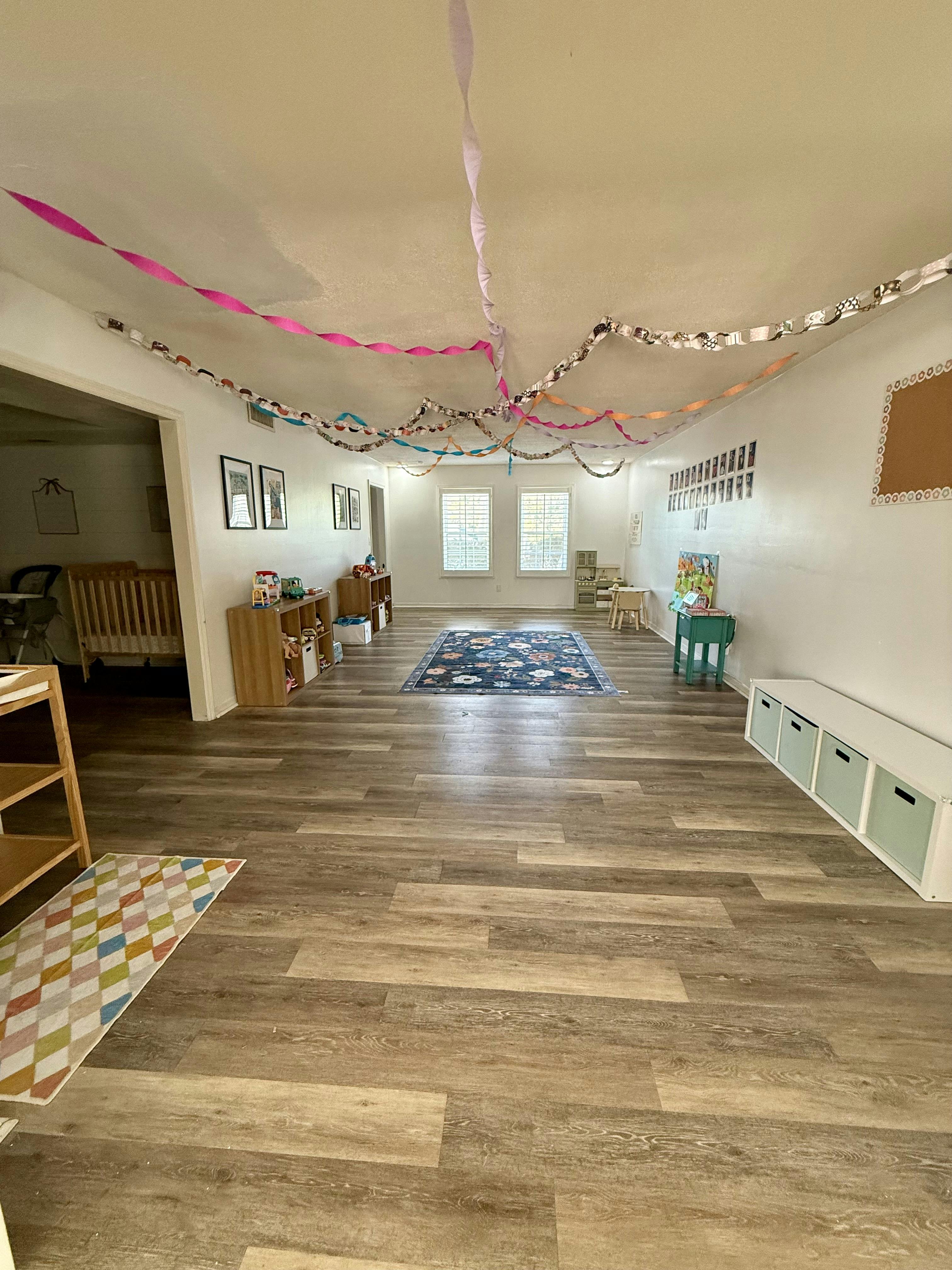 A playroom with wood floors and a crib visible in the background