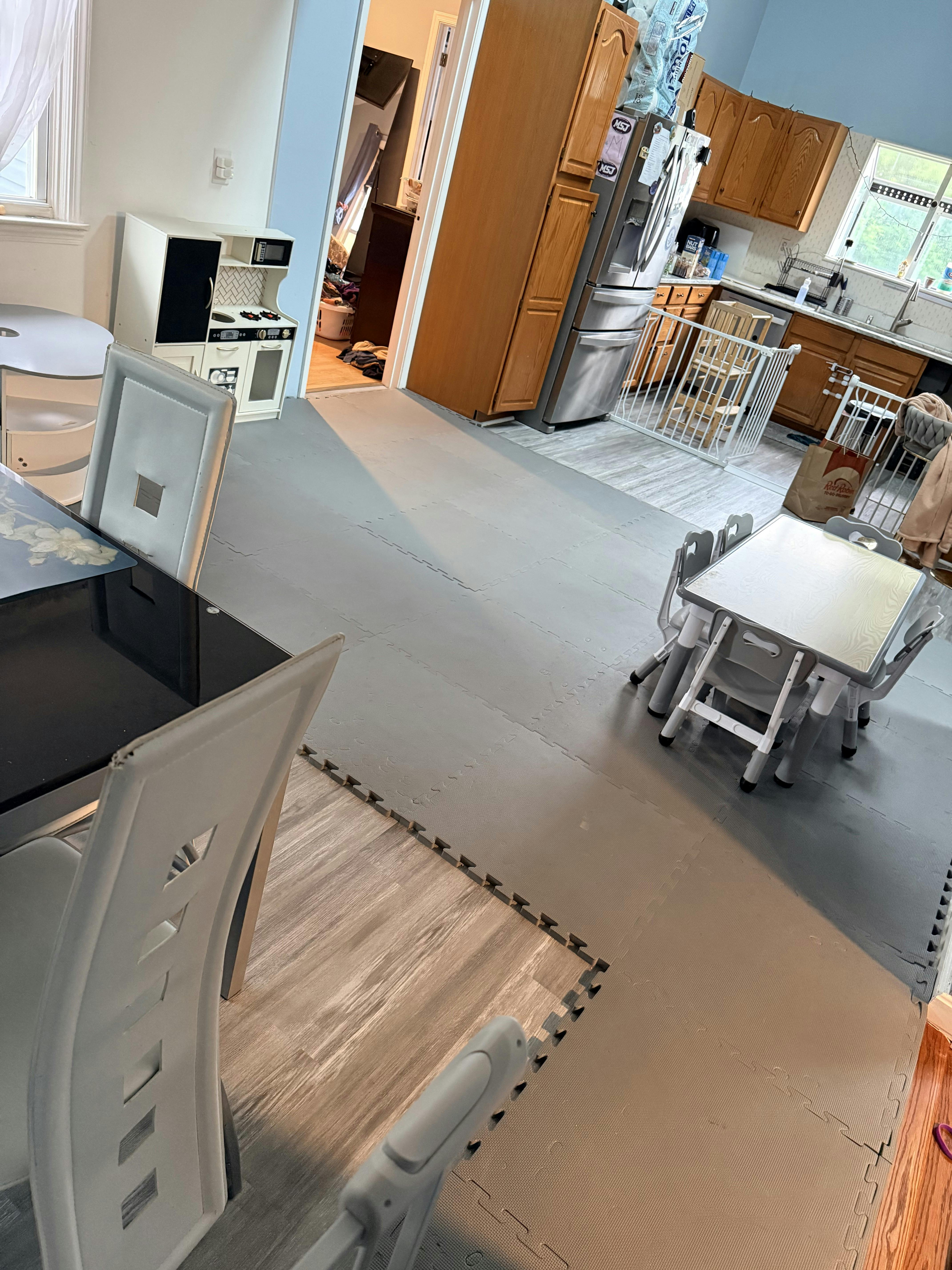 A room with grey foam floor mats containing a small table and chairs