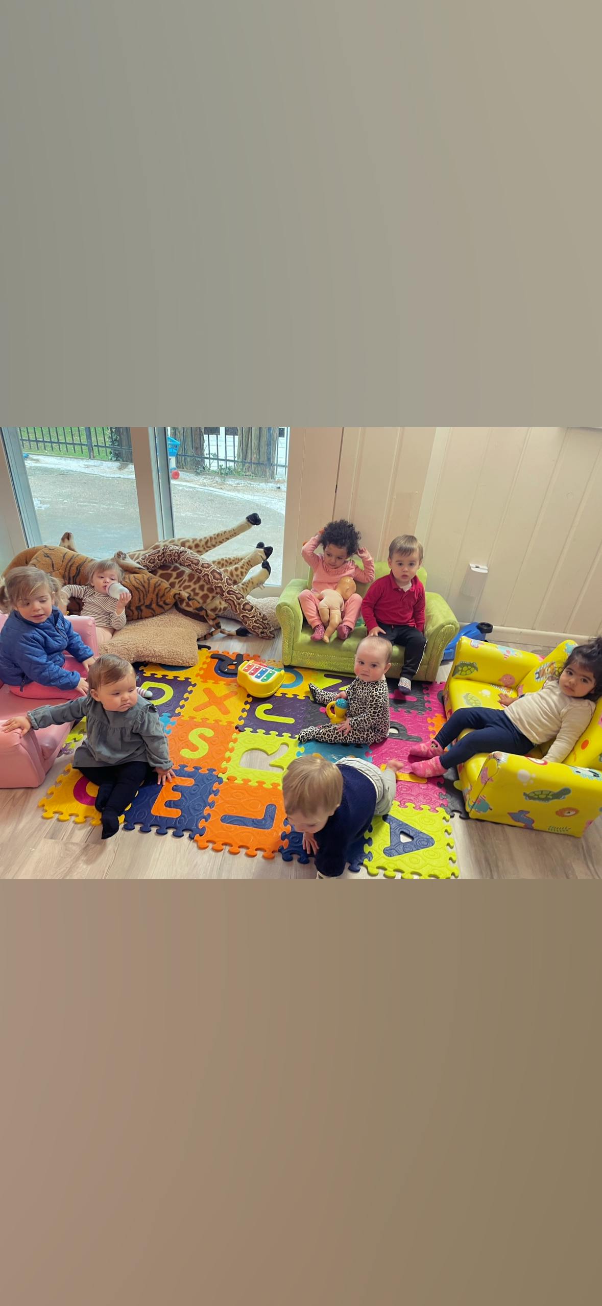 Children playing on a colorful alphabet mat in a room