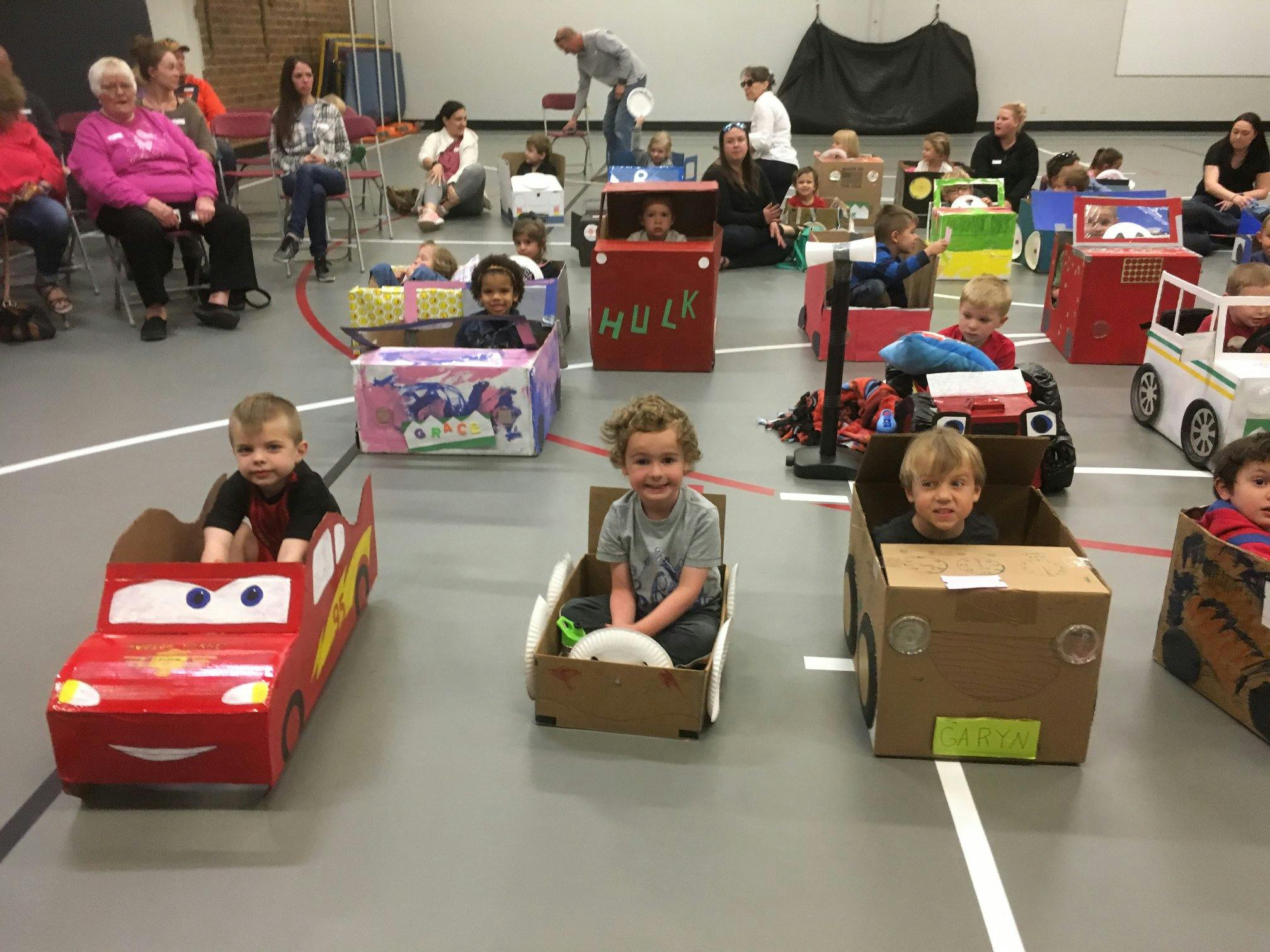 Children sitting in cardboard box cars