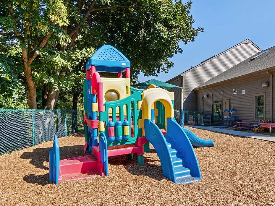 Colorful playground structure with slides and stairs on wood chips