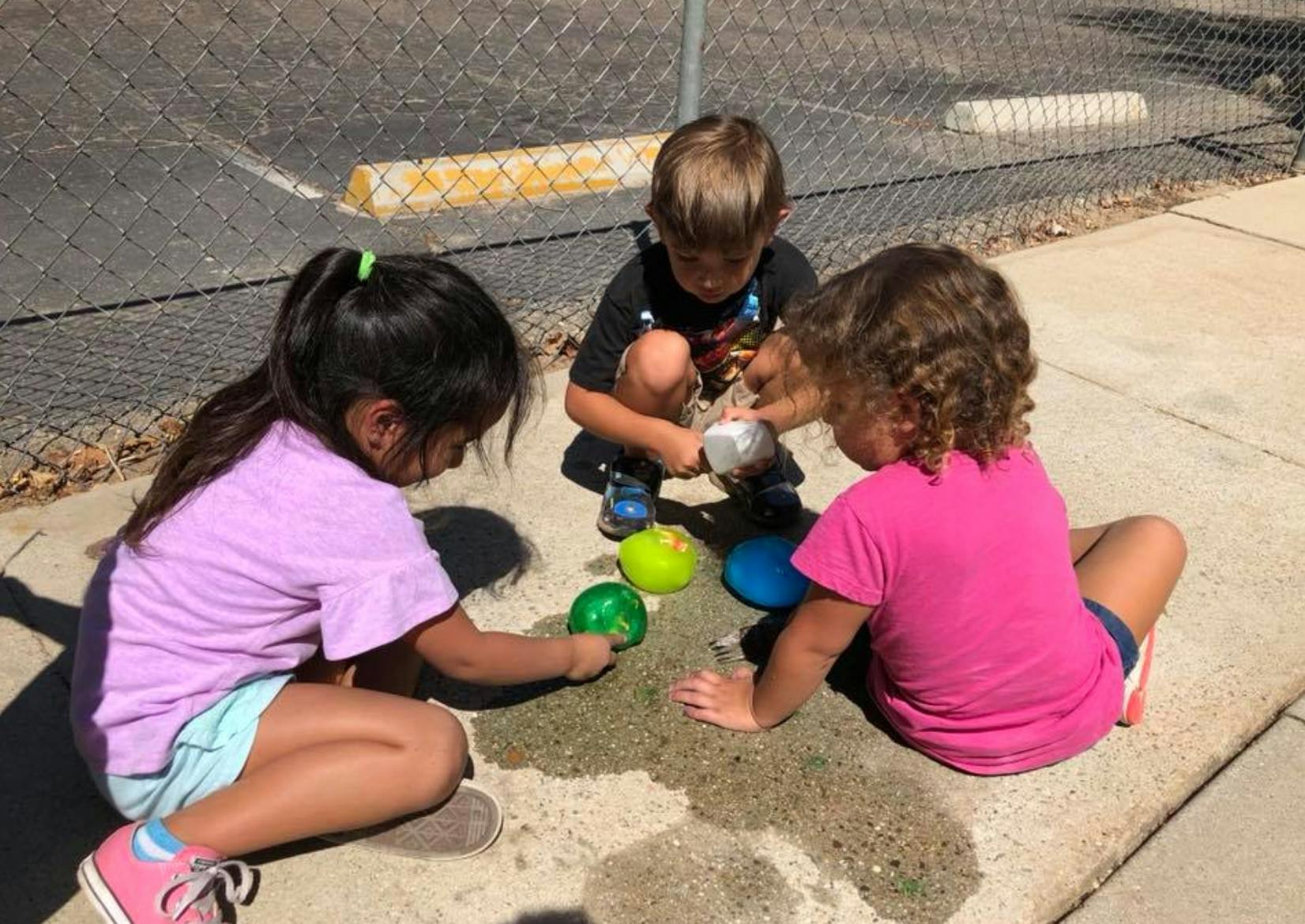 Three children playing with colorful toys on the ground