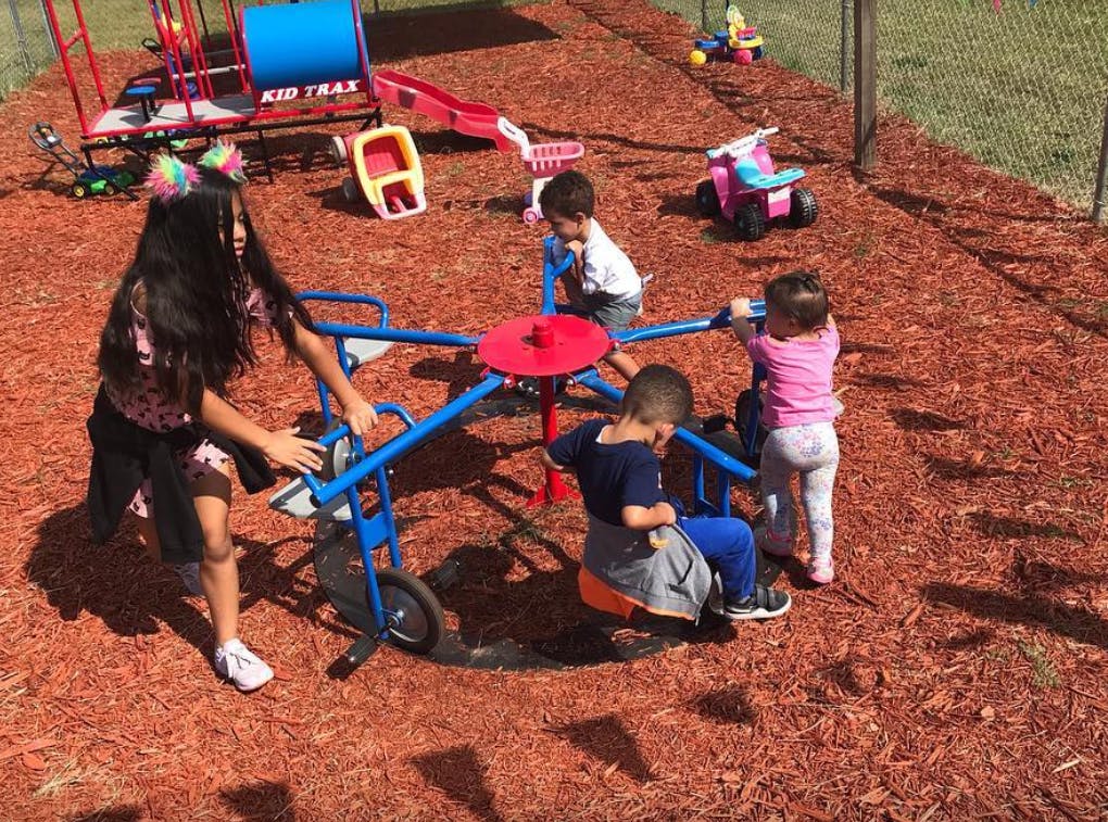 Four children playing on a merry-go-round in a playground
