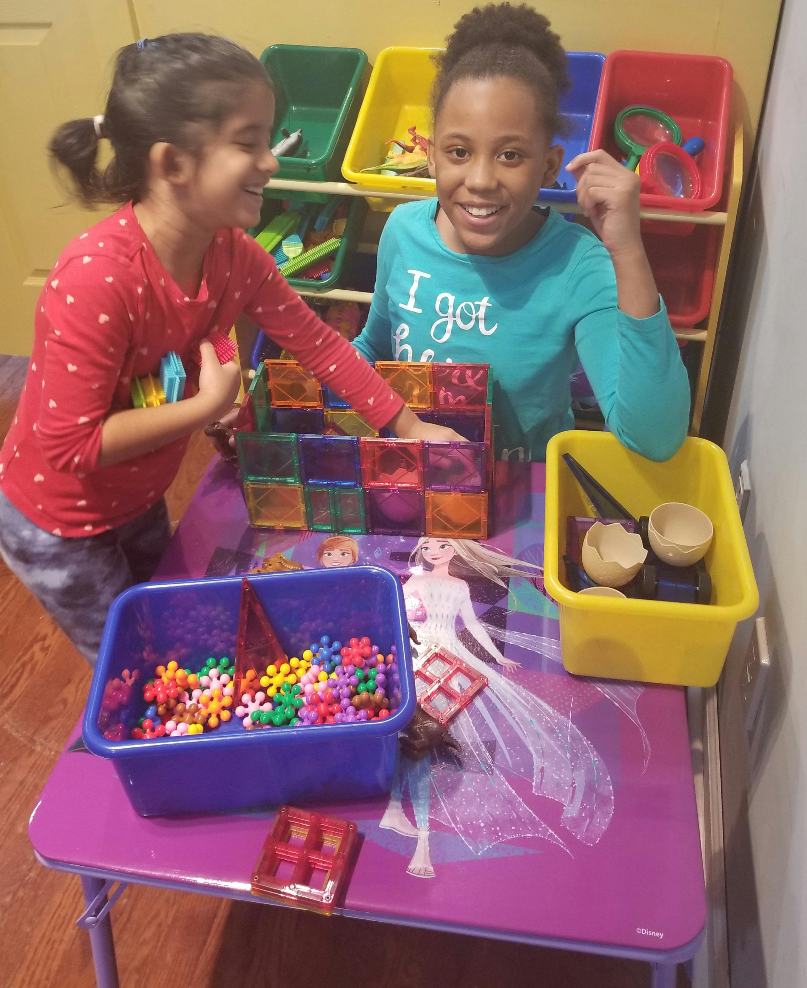 Two children playing with colorful building blocks on a table