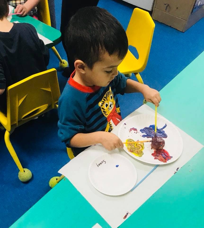 Child painting on paper plates at a table
