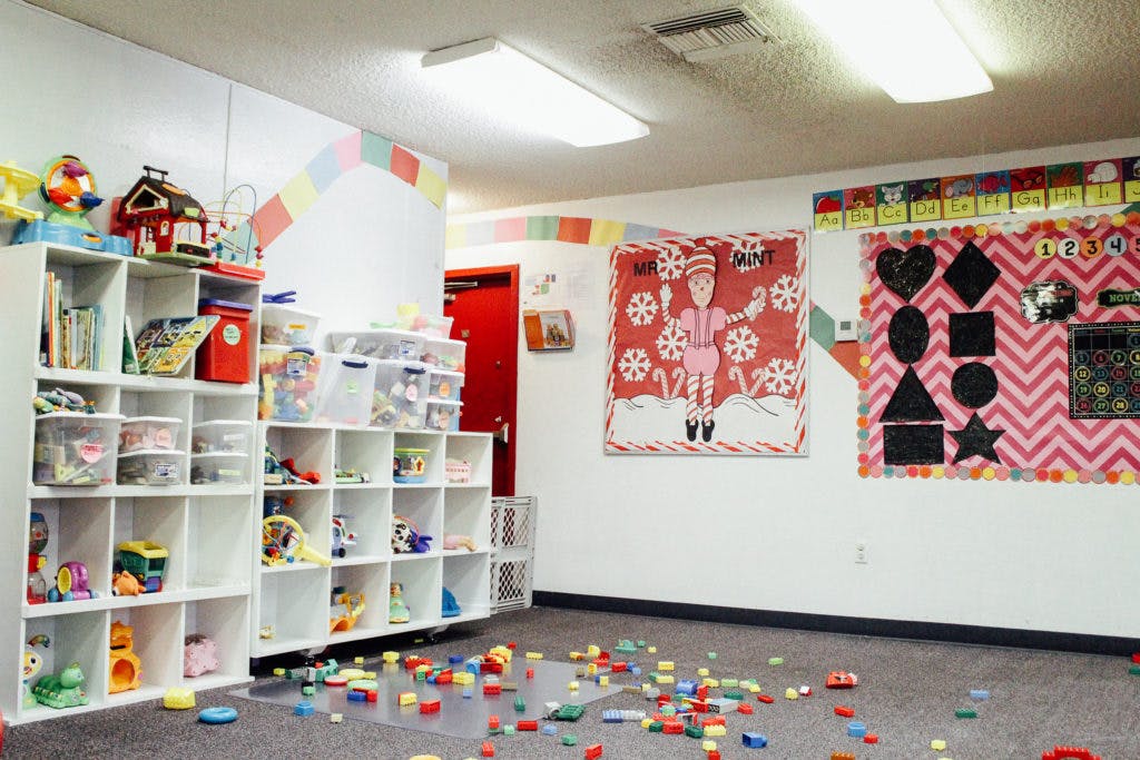 Playroom with shelves of toys and colorful blocks scattered on the floor