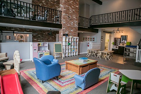 Playroom with small blue chairs, a colorful rug, and a wooden coffee table