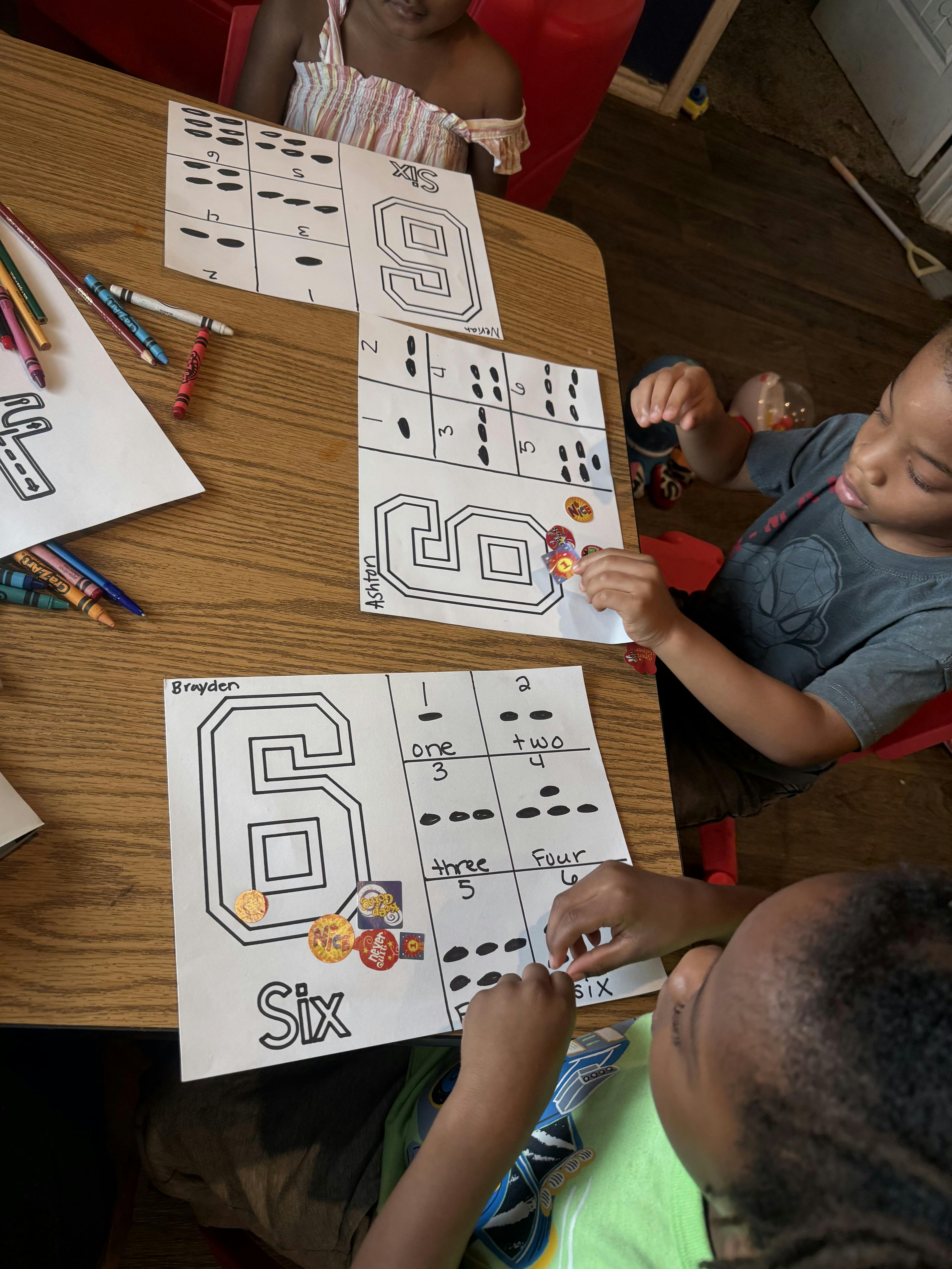 Children learning to count using worksheets with number six