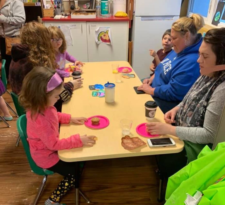 People and children sitting around a table with drinks and snacks