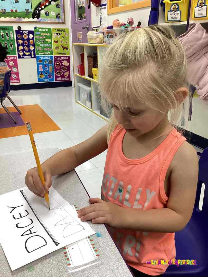 Child drawing with a pencil on a paper with "Dacey" written on it