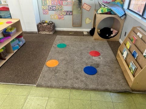 Classroom with rug, shelves, and a child in a wooden cubby