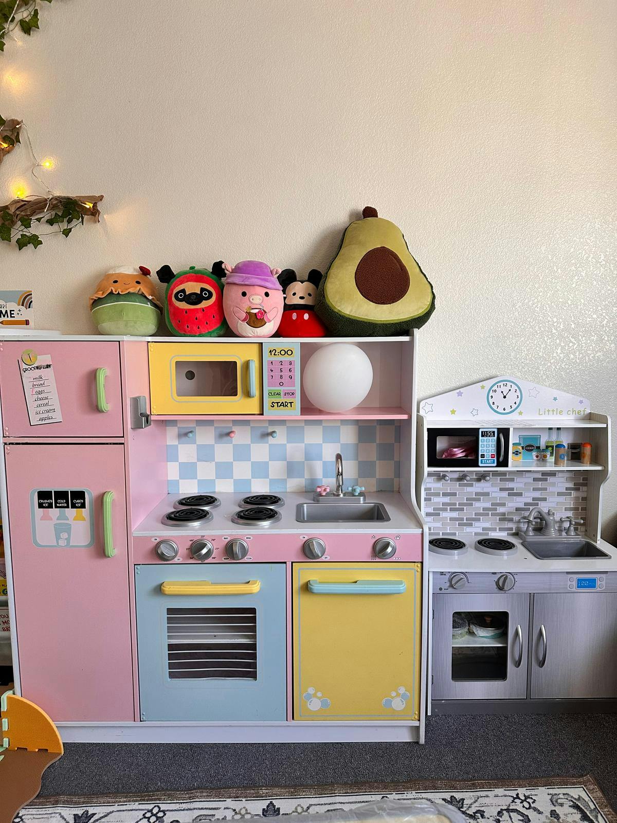 Plush toys sitting on top of two toy kitchen play sets