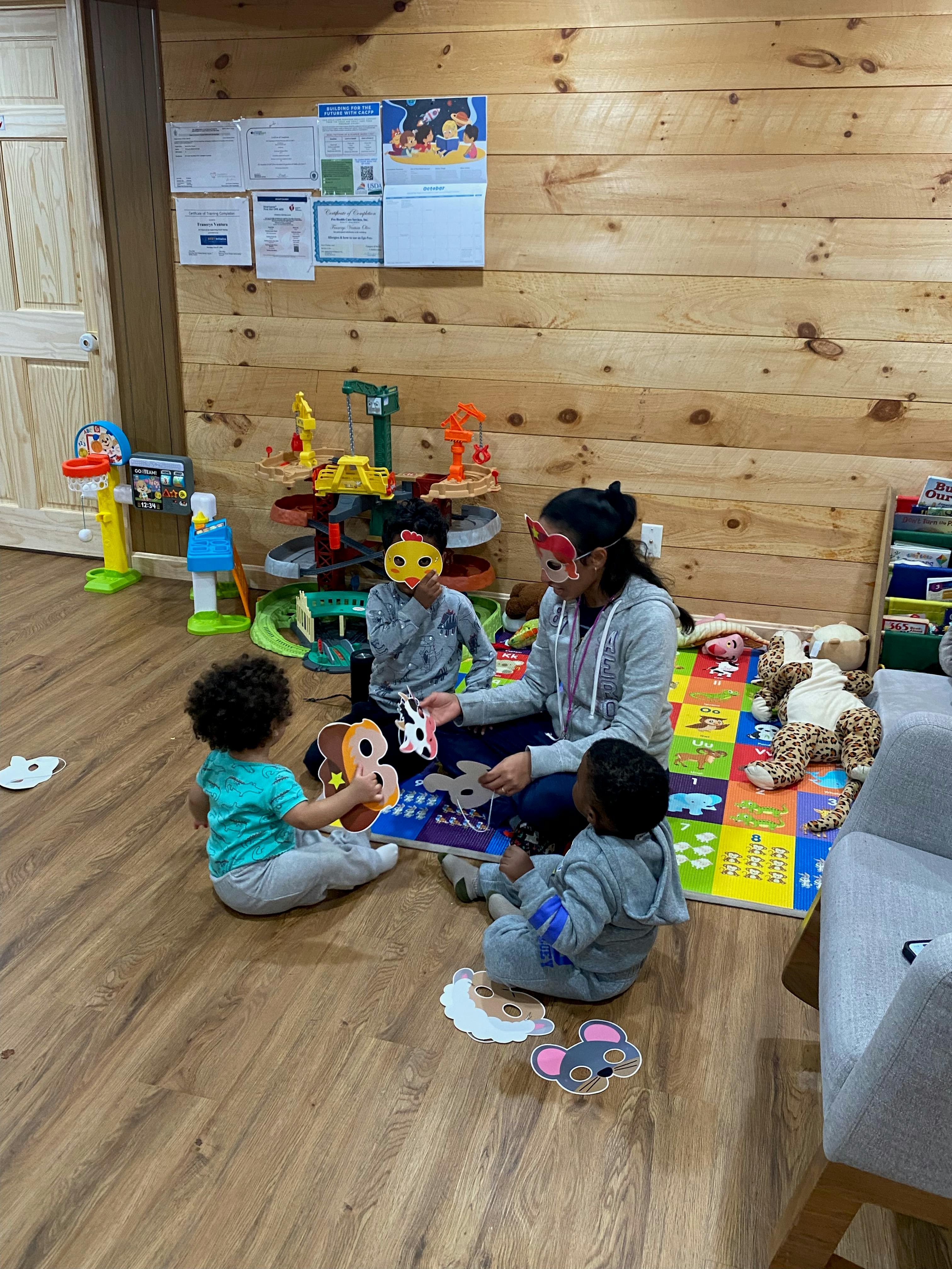 Person and three children playing with toys on a mat