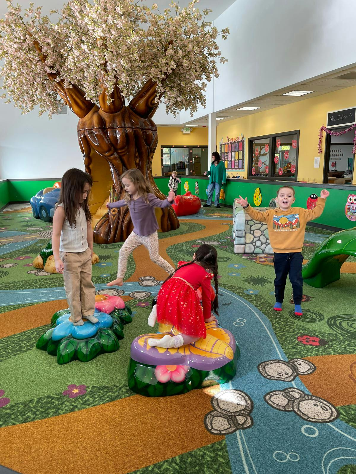 Children playing on flower-shaped platforms in an indoor play area