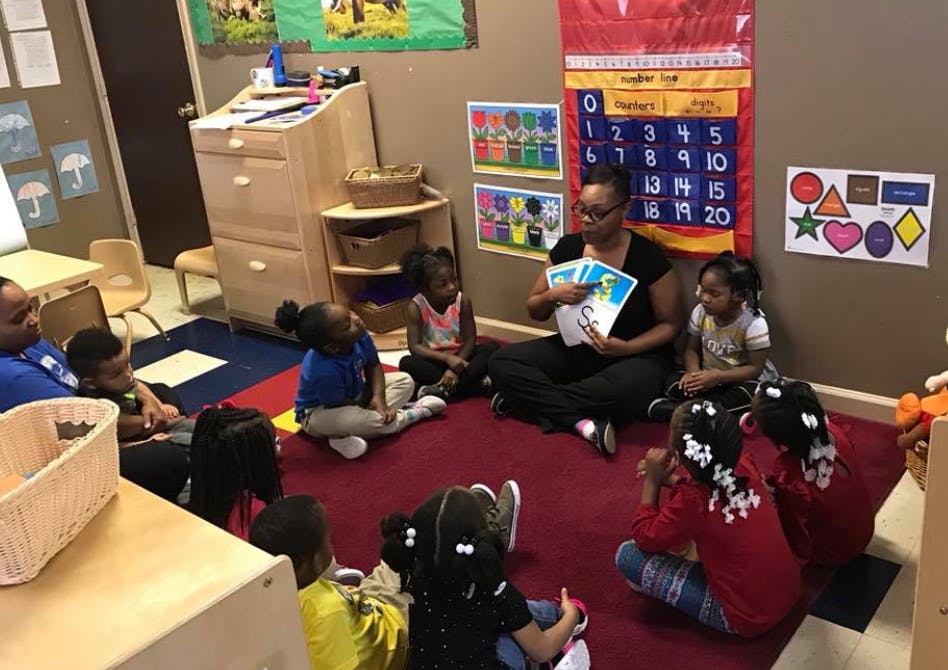Adult reading to children sitting on a rug in a classroom