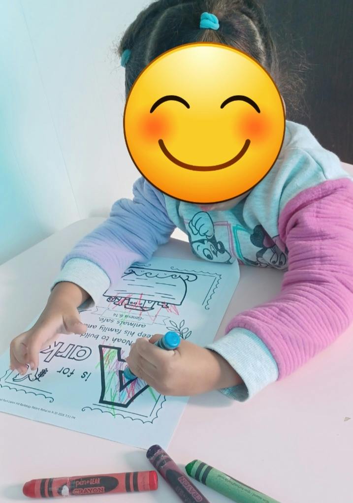 Child coloring on a paper with the text A is for Ark