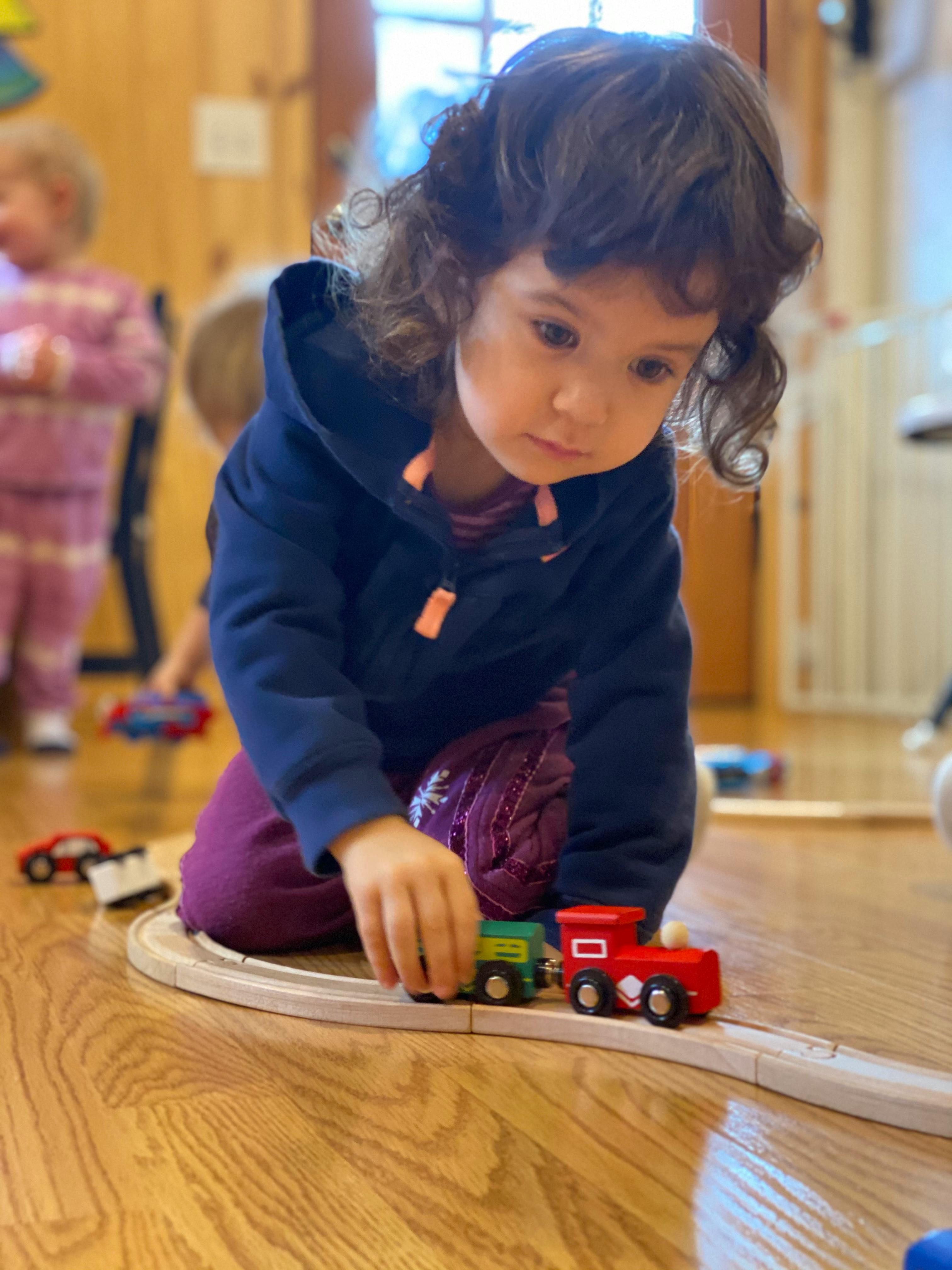 Child playing with a toy train on a wooden track