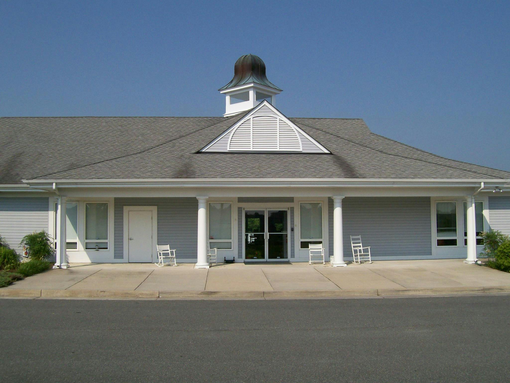Building with a gray roof, white columns, and a small cupola