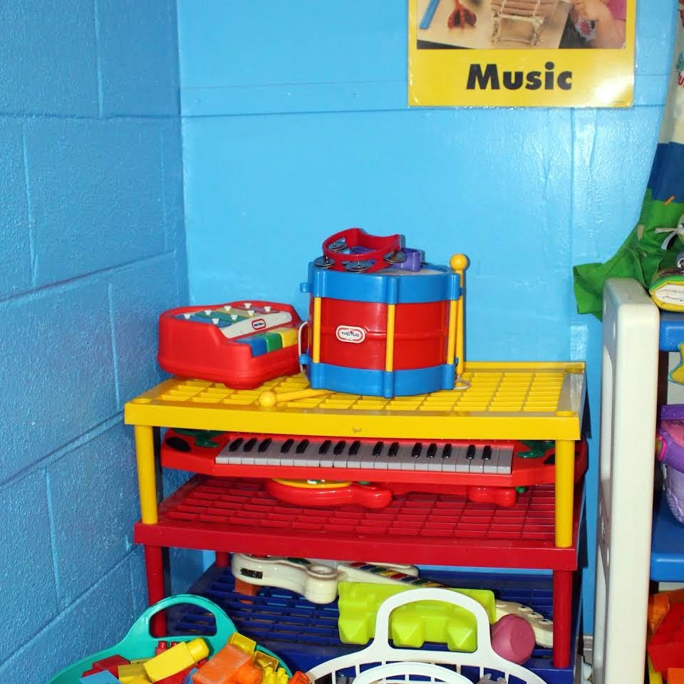 Children's musical instruments on shelves, under, and around a red and yellow shelf