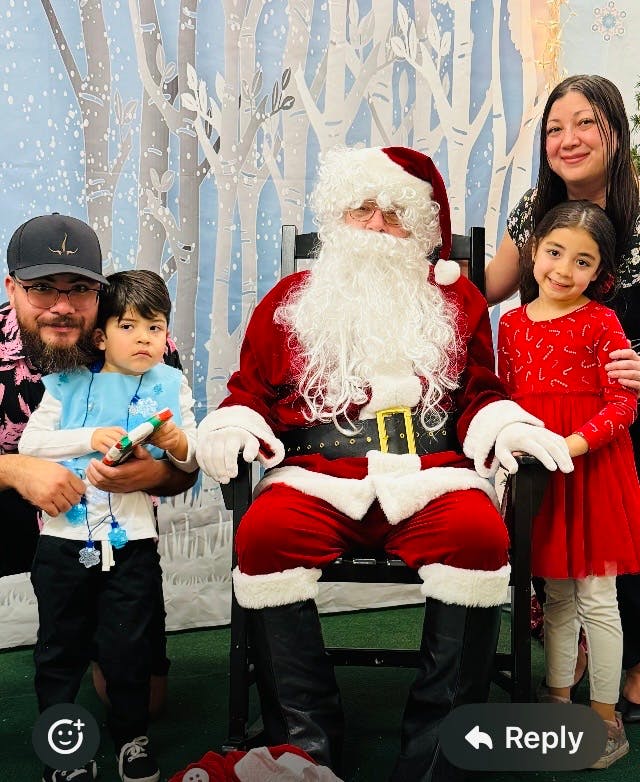 Santa Claus sitting in a chair with two people and two children